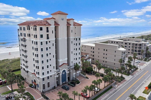 view of building exterior with a beach view and a water view