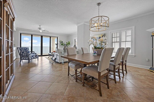 tiled dining area with ceiling fan with notable chandelier, ornamental molding, and a textured ceiling