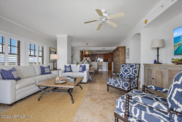 living room with ceiling fan, a textured ceiling, light tile patterned flooring, and ornamental molding