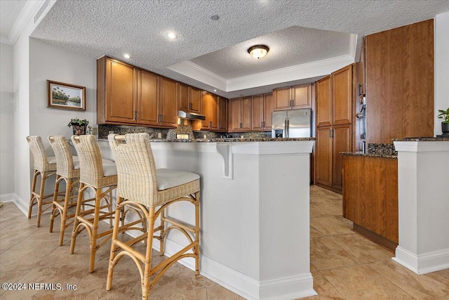 kitchen with stainless steel fridge with ice dispenser, light tile patterned flooring, dark stone counters, and kitchen peninsula