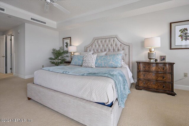 bedroom with ornamental molding, a textured ceiling, light carpet, a tray ceiling, and ceiling fan