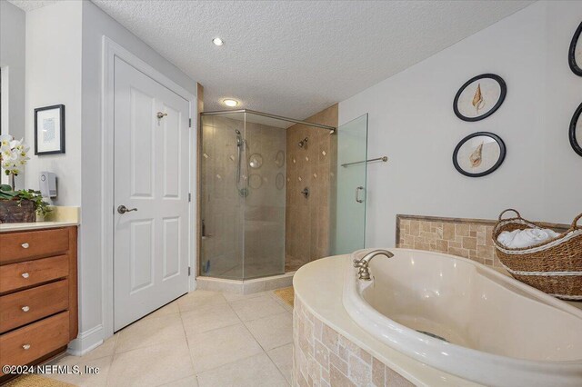 bathroom with tile patterned flooring, a textured ceiling, vanity, and shower with separate bathtub