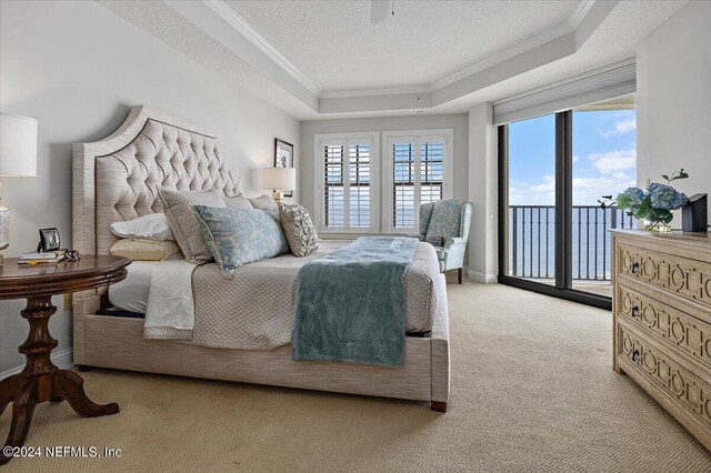 bedroom with crown molding, a textured ceiling, access to exterior, a tray ceiling, and light carpet