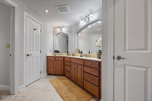 bathroom with a textured ceiling, vanity, and tile patterned floors