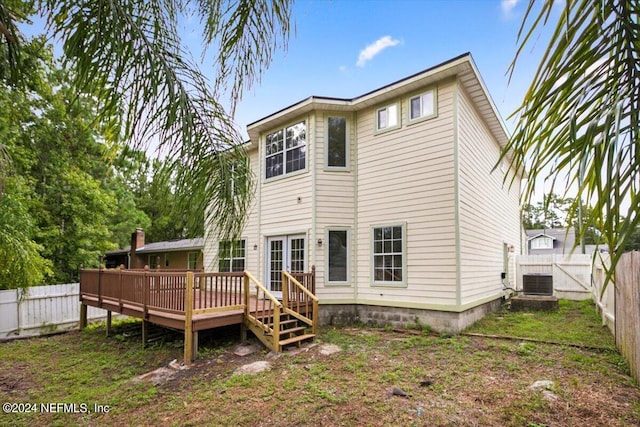 back of property featuring cooling unit, a wooden deck, and a lawn