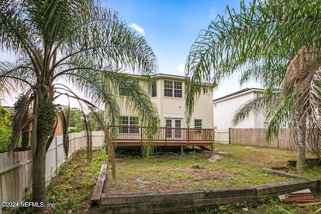 rear view of house featuring a lawn and a wooden deck