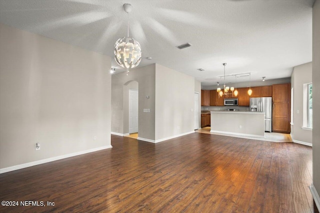 unfurnished living room with hardwood / wood-style floors, an inviting chandelier, and a textured ceiling