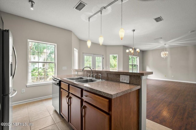 kitchen with appliances with stainless steel finishes, light tile patterned floors, a textured ceiling, and a healthy amount of sunlight