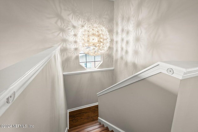 stairway featuring hardwood / wood-style flooring and an inviting chandelier