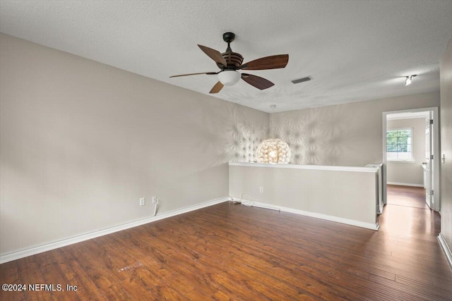 empty room featuring dark wood-type flooring, a textured ceiling, and ceiling fan