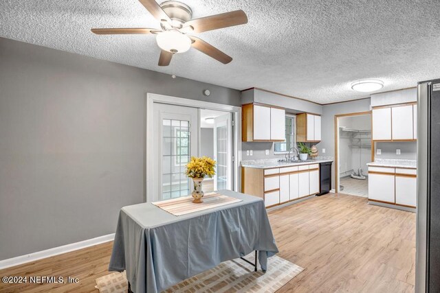 kitchen with ceiling fan, a textured ceiling, white cabinetry, and light hardwood / wood-style floors