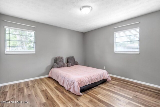 bedroom with light hardwood / wood-style flooring and multiple windows