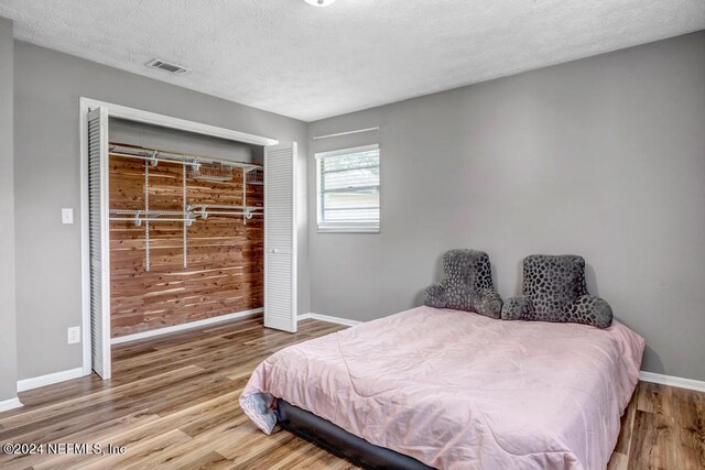 bedroom featuring wood-type flooring, a closet, and a textured ceiling