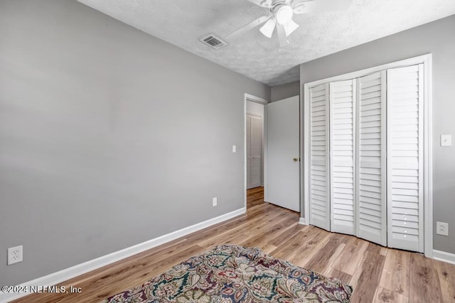 bedroom featuring ceiling fan, a closet, light hardwood / wood-style floors, and a textured ceiling