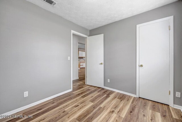 unfurnished bedroom featuring a textured ceiling and light hardwood / wood-style flooring