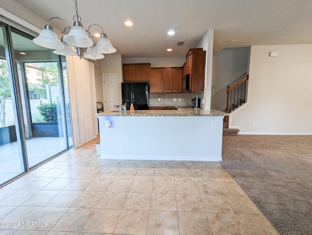 kitchen featuring decorative backsplash, black appliances, pendant lighting, a notable chandelier, and light carpet