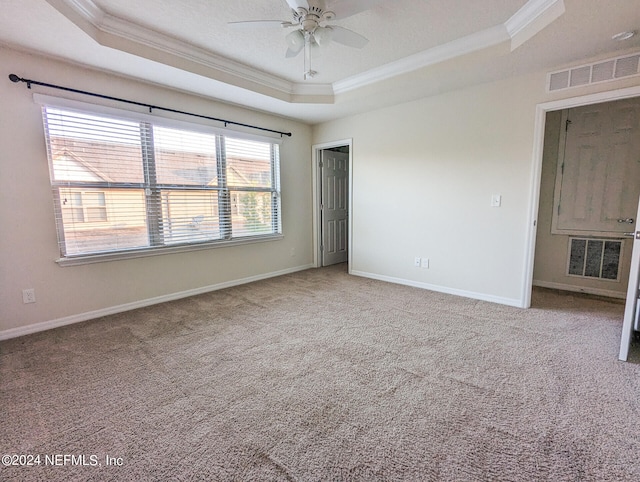 spare room with ceiling fan, carpet flooring, a tray ceiling, and ornamental molding