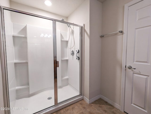 bathroom with an enclosed shower and tile patterned floors