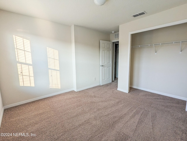 unfurnished bedroom with a closet and light colored carpet