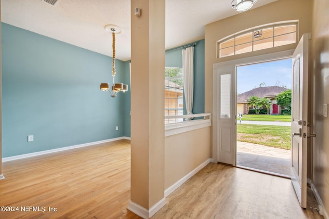 entryway featuring a textured ceiling, light hardwood / wood-style flooring, and a notable chandelier