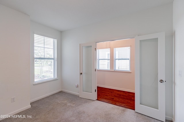 unfurnished bedroom with french doors, light wood-type flooring, and multiple windows