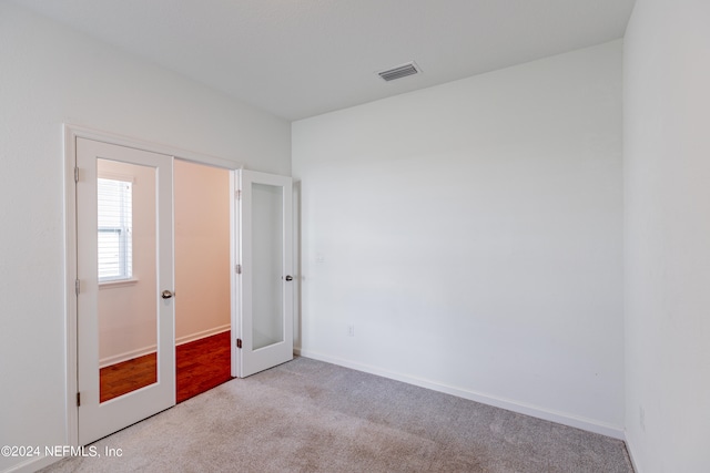 unfurnished bedroom with light carpet and french doors