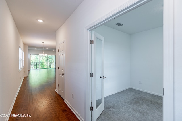 hallway with an inviting chandelier and hardwood / wood-style floors