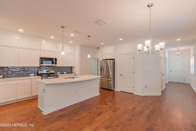 kitchen featuring a kitchen island with sink, decorative light fixtures, stainless steel appliances, and light hardwood / wood-style floors