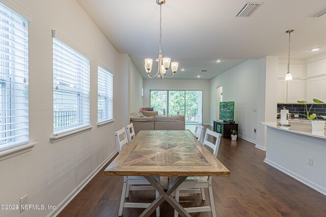 dining area with dark wood-type flooring and an inviting chandelier