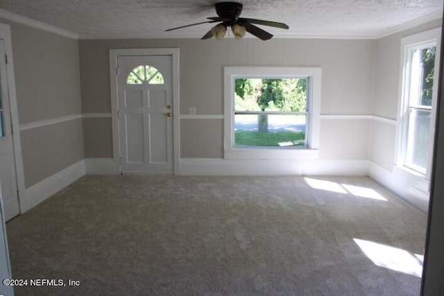 foyer with carpet flooring, a textured ceiling, ceiling fan, and crown molding