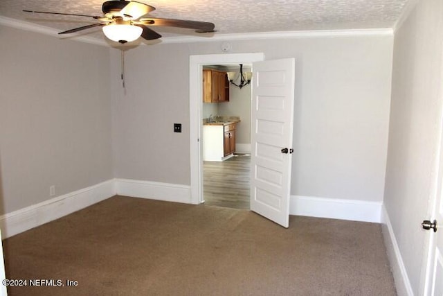 carpeted empty room featuring ceiling fan, a textured ceiling, sink, and crown molding