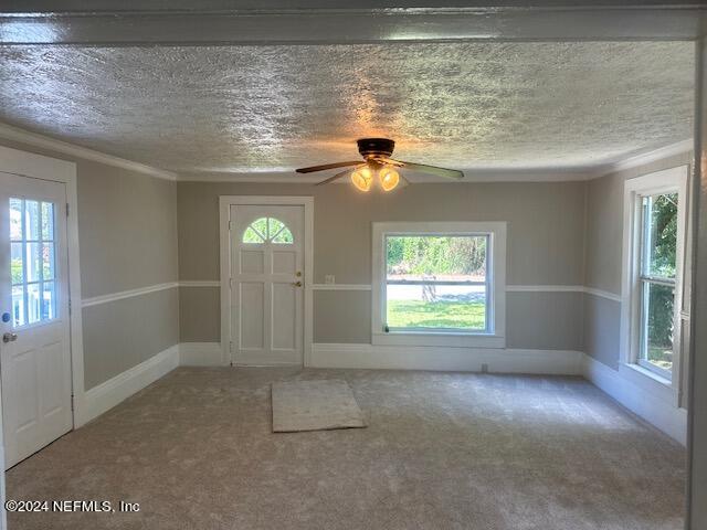 entrance foyer featuring a textured ceiling, carpet floors, ceiling fan, and crown molding