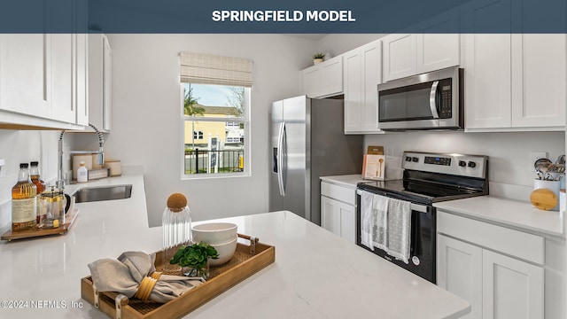 kitchen featuring light countertops, appliances with stainless steel finishes, a sink, and white cabinets