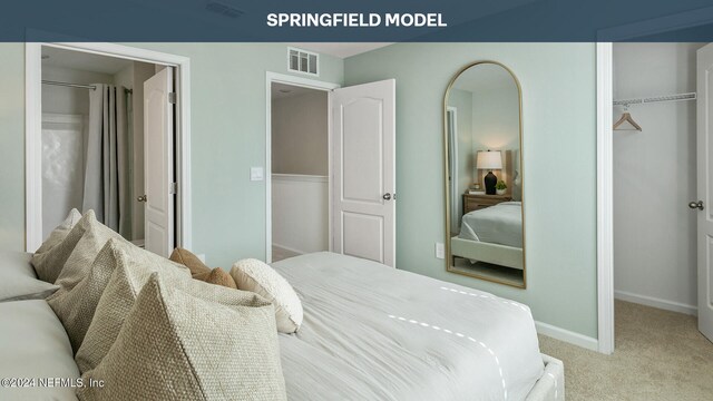 bedroom featuring baseboards, visible vents, light colored carpet, a walk in closet, and a closet