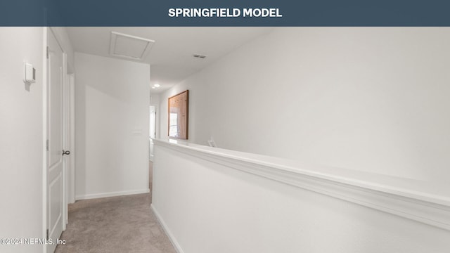 corridor with light carpet, visible vents, baseboards, and attic access