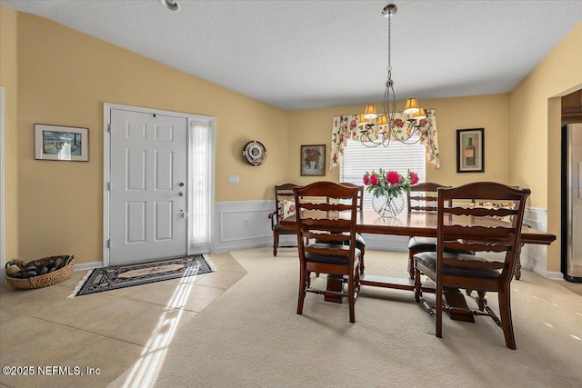 dining room with a chandelier, light carpet, a textured ceiling, and lofted ceiling