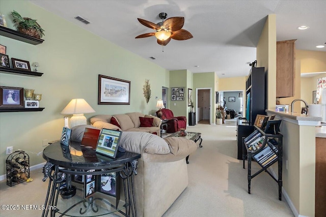 living room with light carpet, ceiling fan, and sink