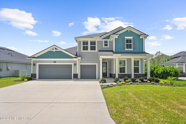 craftsman house featuring a garage, covered porch, and a front yard