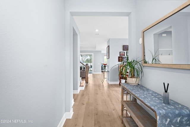 hallway featuring baseboards, stairway, and light wood-style floors