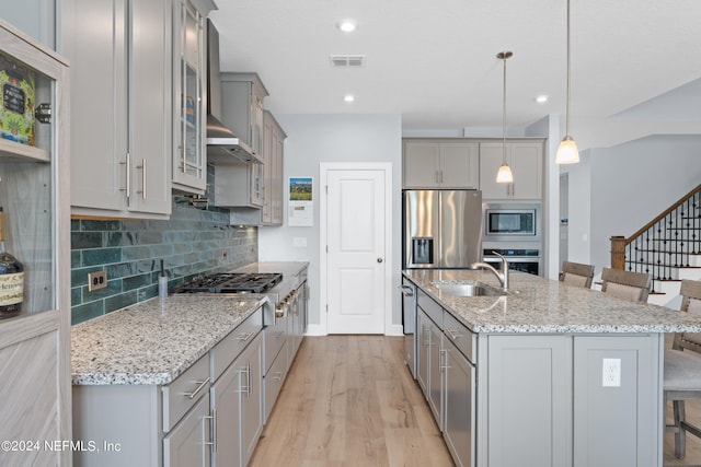 kitchen with tasteful backsplash, appliances with stainless steel finishes, gray cabinetry, a kitchen bar, and a sink