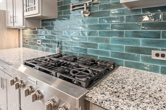 kitchen with stainless steel range oven, light stone counters, and decorative backsplash