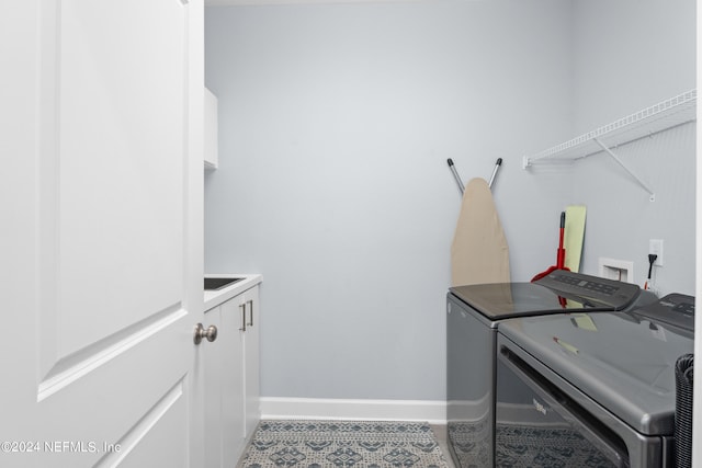 clothes washing area featuring cabinet space, baseboards, washer and clothes dryer, and tile patterned floors