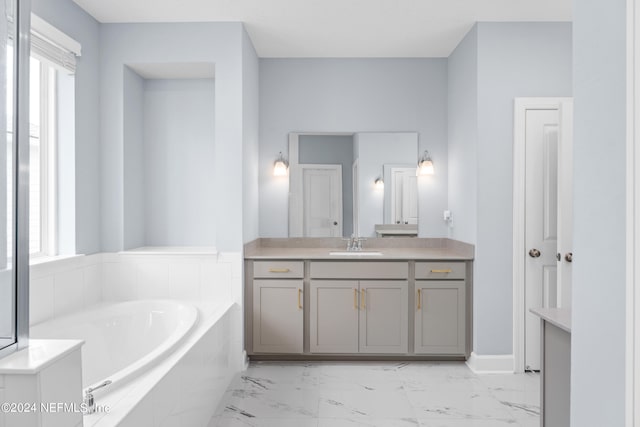 bathroom featuring tiled tub and vanity