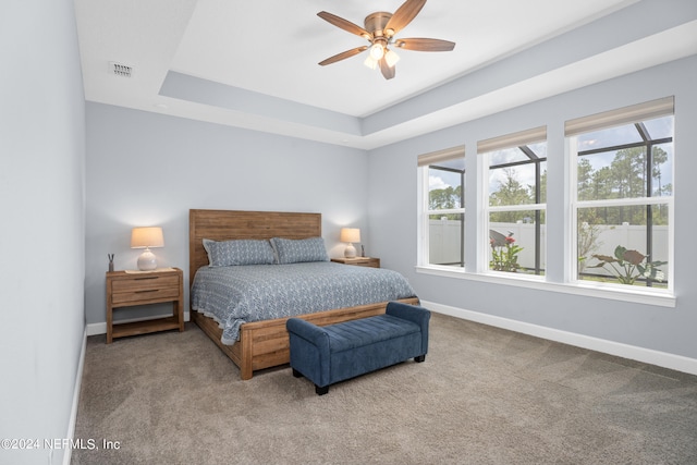 carpeted bedroom featuring ceiling fan, baseboards, visible vents, and a raised ceiling