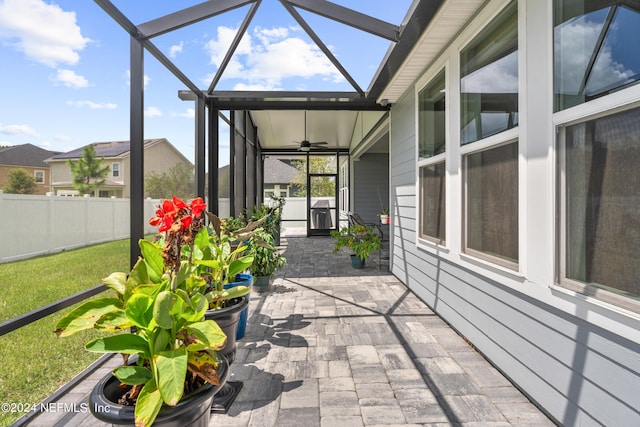 view of patio with glass enclosure, fence, and a ceiling fan