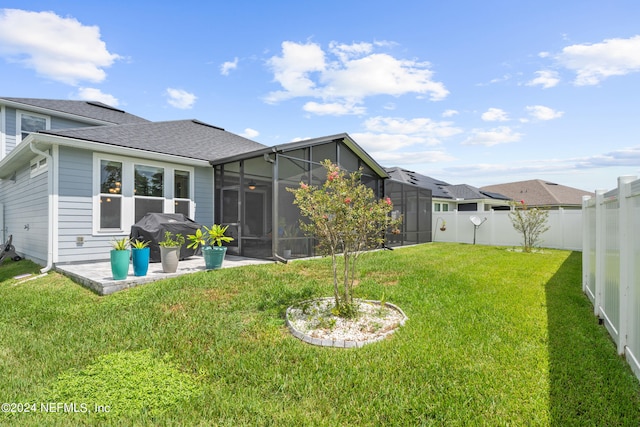 rear view of house with a fenced backyard, a sunroom, roof with shingles, a lawn, and a patio area