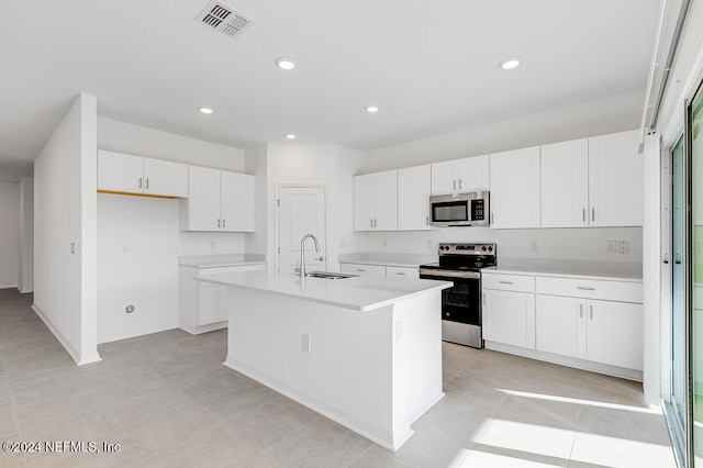 kitchen with appliances with stainless steel finishes, a center island with sink, white cabinetry, and sink