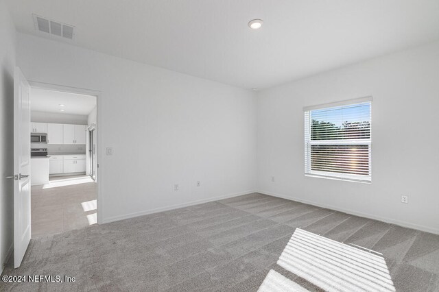 empty room with light carpet and vaulted ceiling