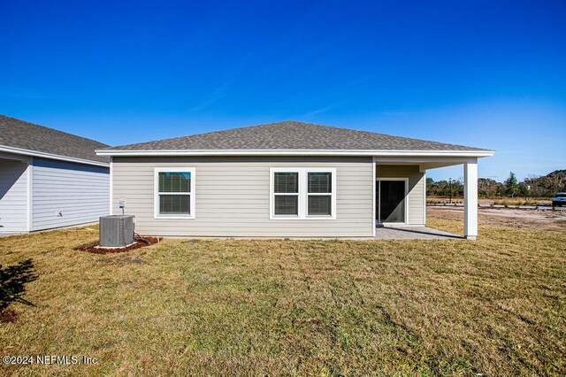 rear view of property featuring central AC unit, a yard, and a patio