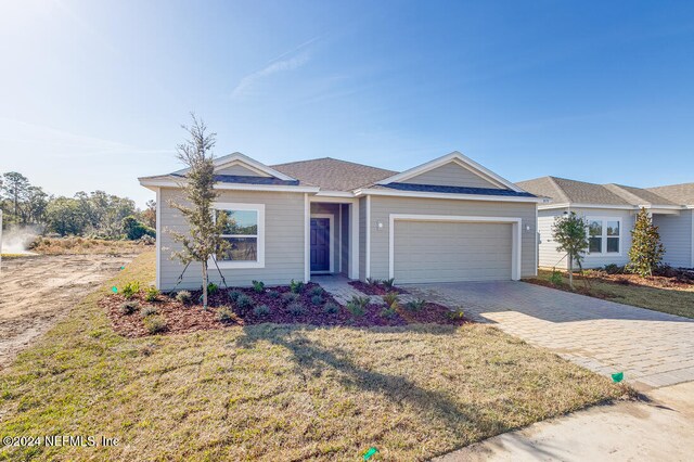 ranch-style home featuring a garage and a front lawn